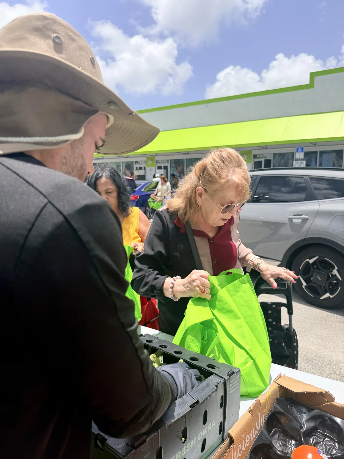 Volunteer handing a bag of groceries to a neighbor through a car window